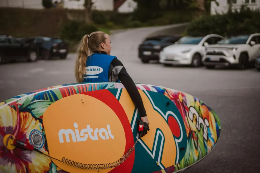 Person carrying an inflatable paddleboard towards a lake