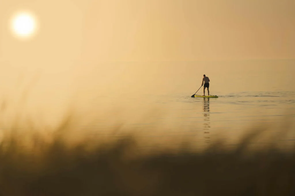 Stand up paddleboarder on a calm UK lake with gear