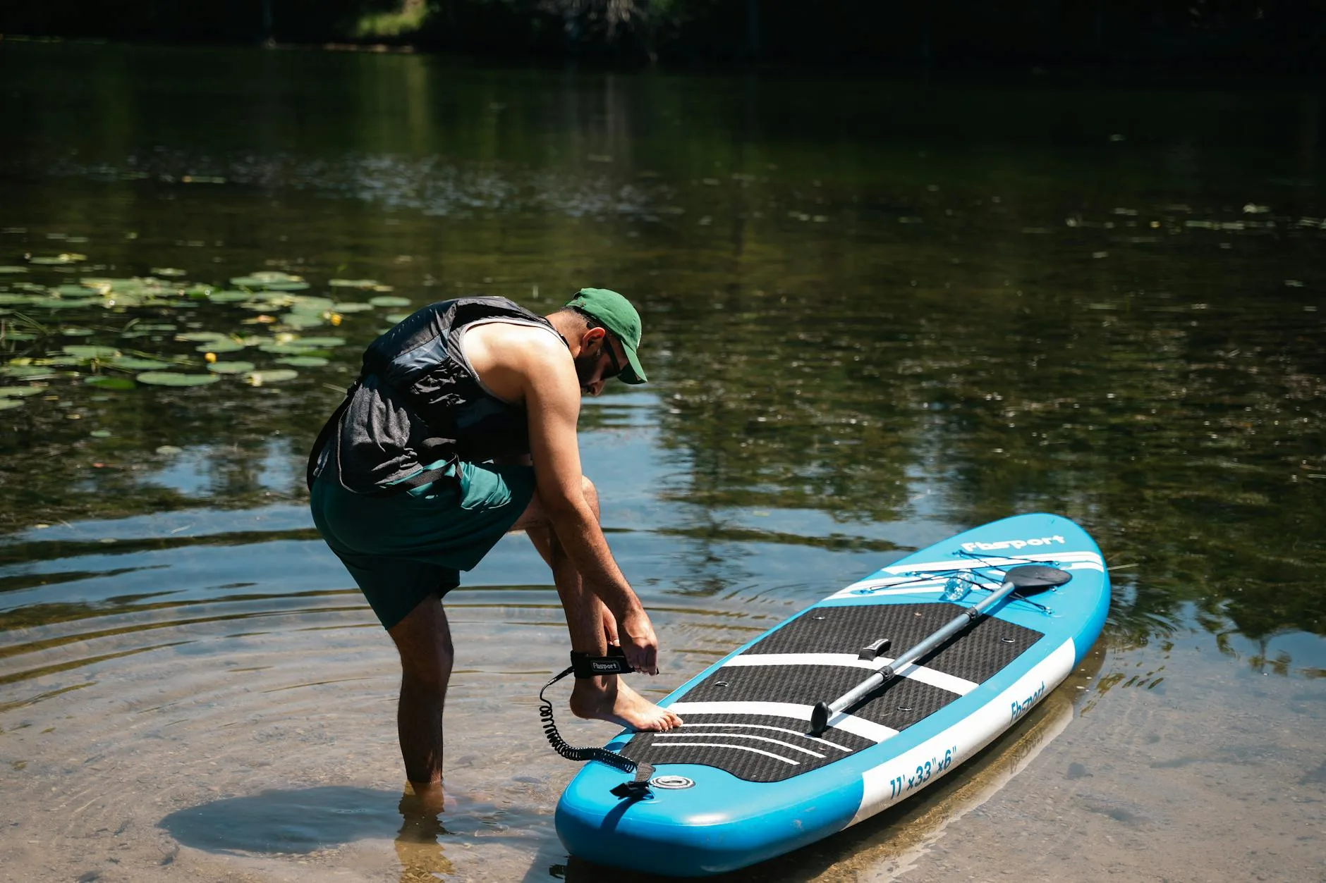 Person carrying a paddleboard and paddle to the water