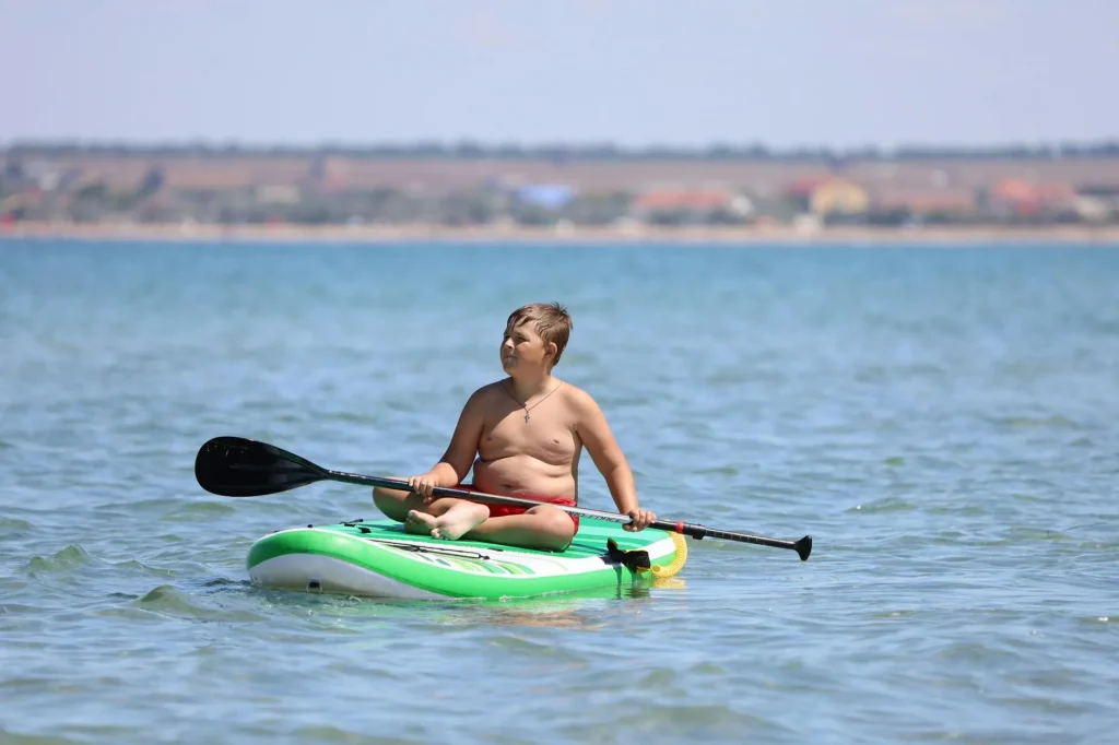 Child paddleboarding on a calm lake on a sunny summer day