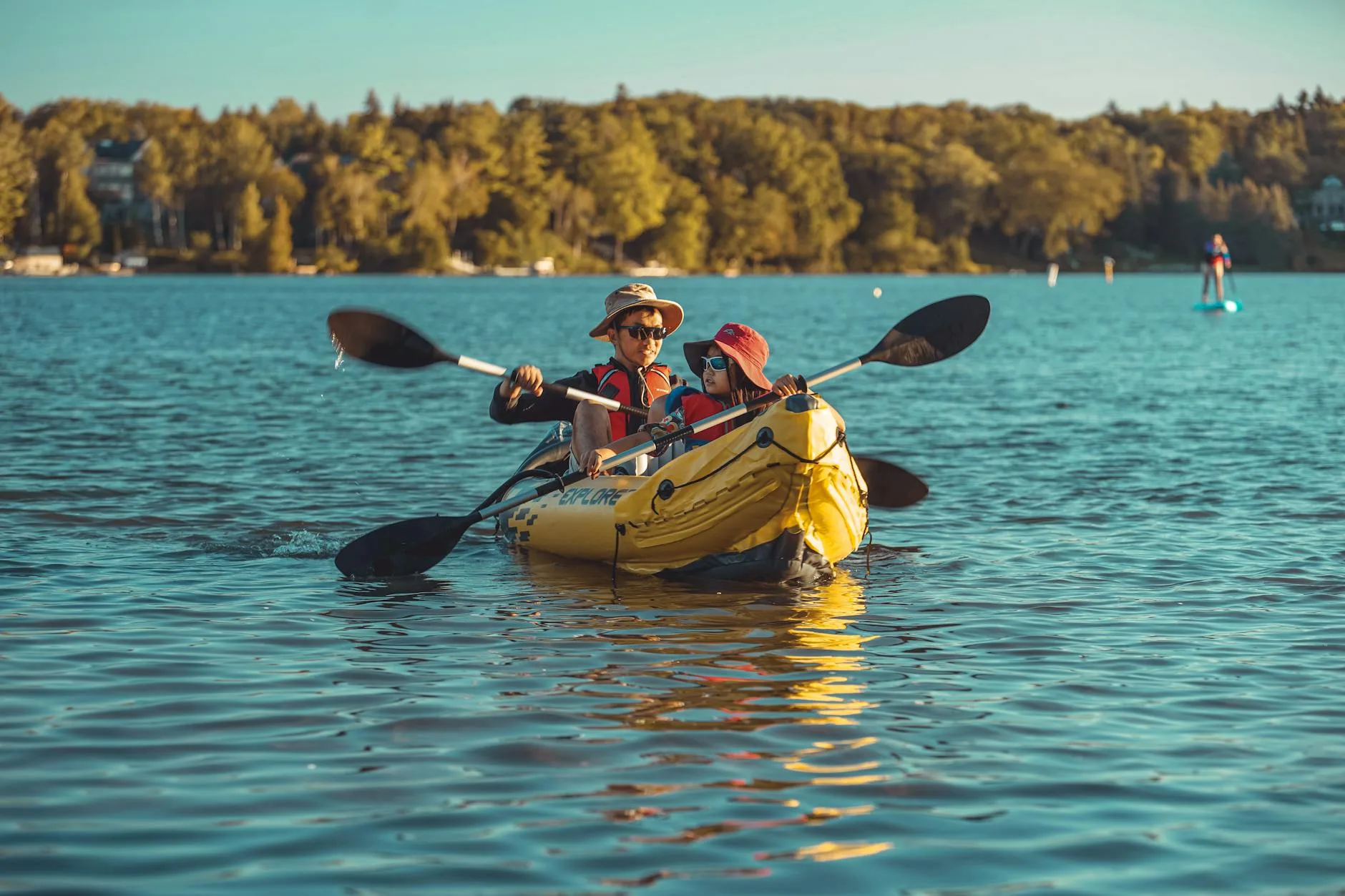 Family kayaking together on a river with children using kid-sized paddles