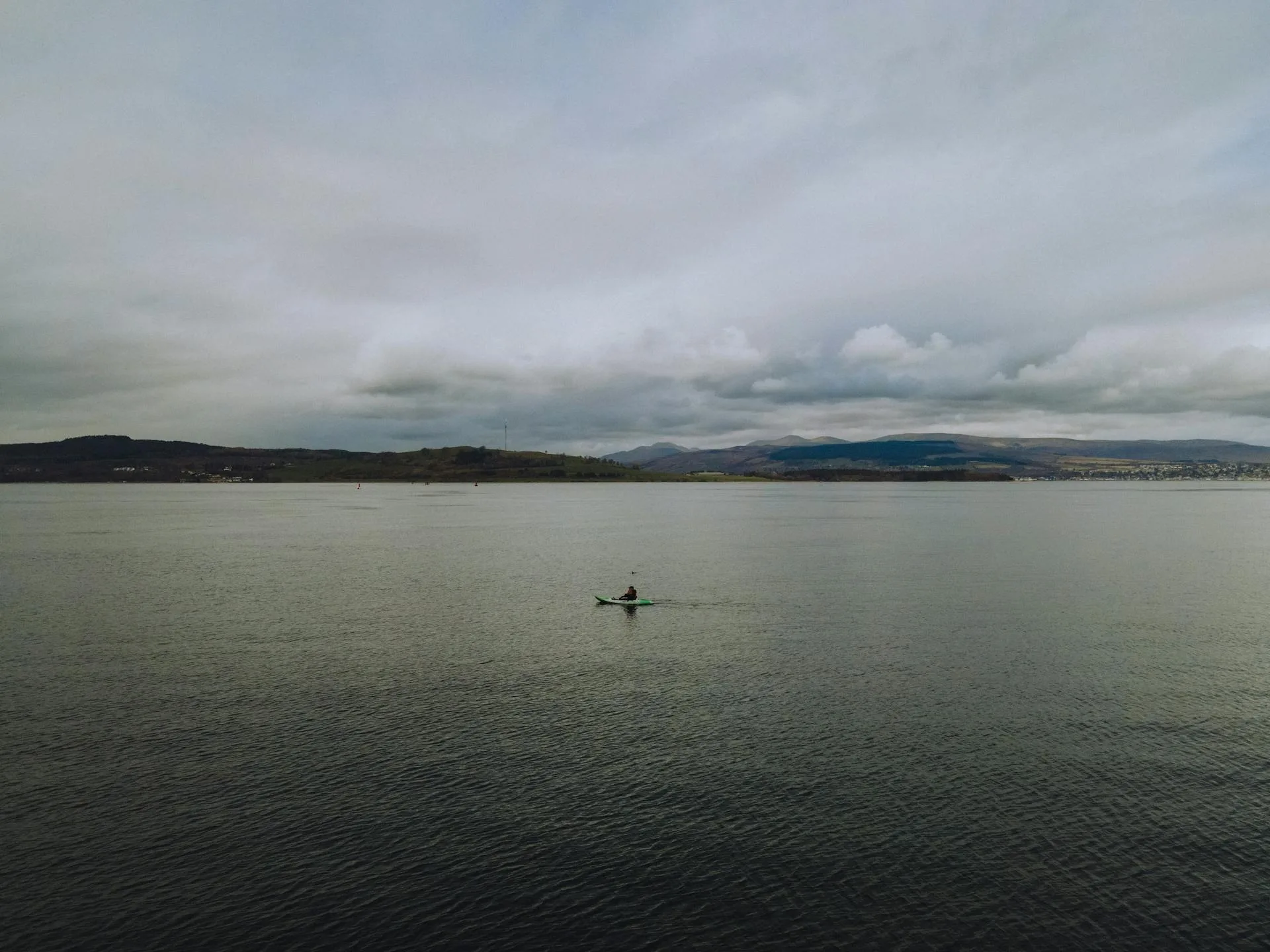 Lone kayaker paddling on calm flat water ideal for flat hull kayaks