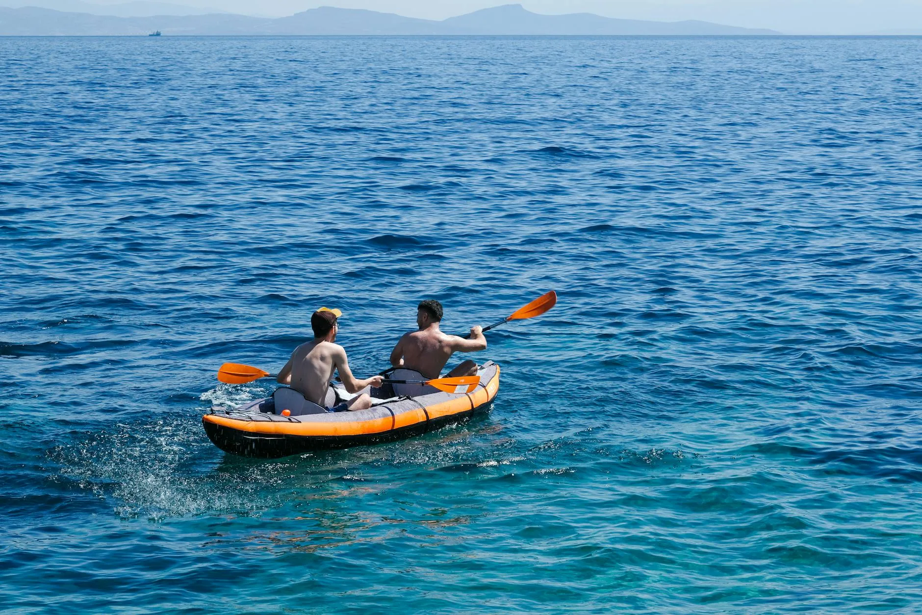 Two people paddling an inflatable kayak on a river