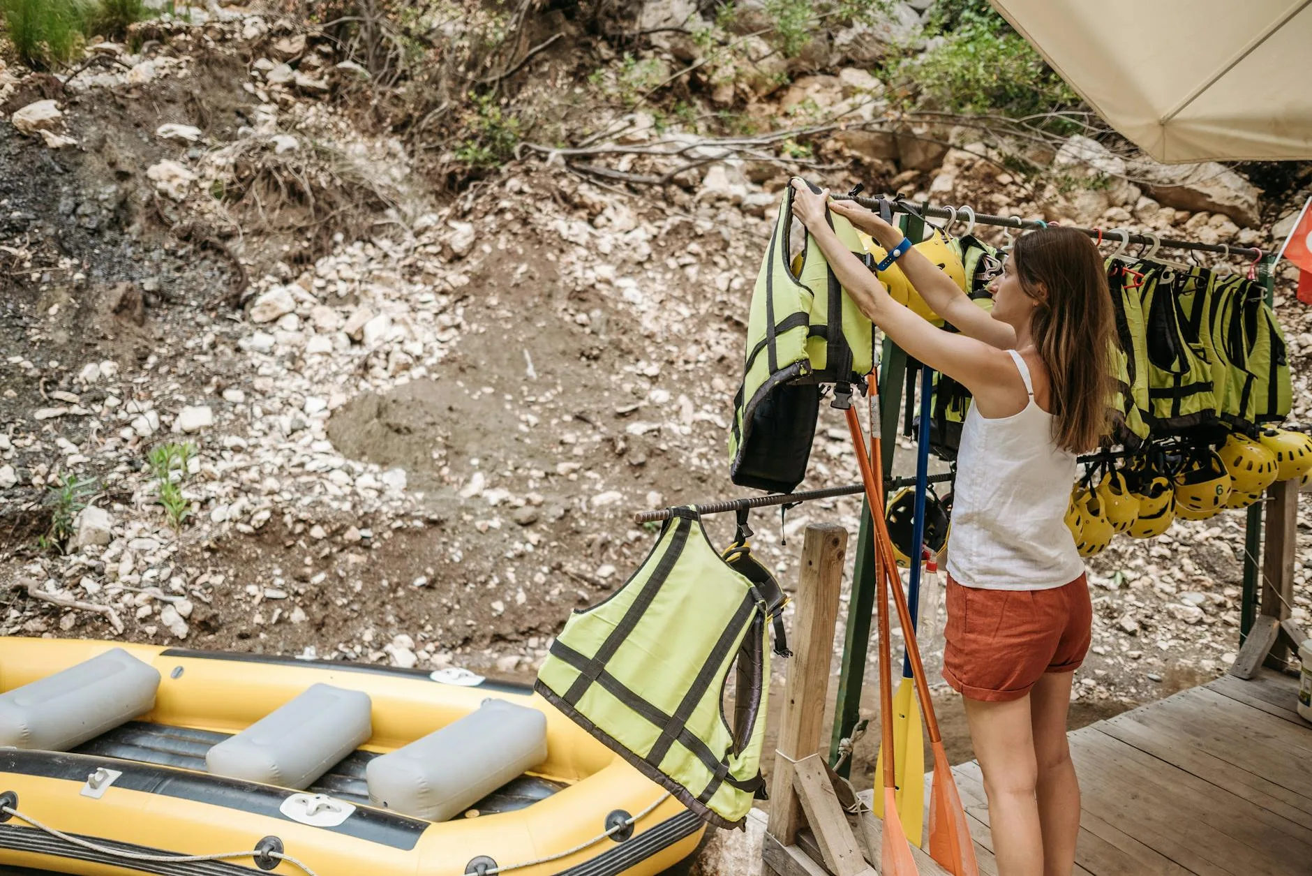 Person inflating a kayak with a hand pump at a riverside