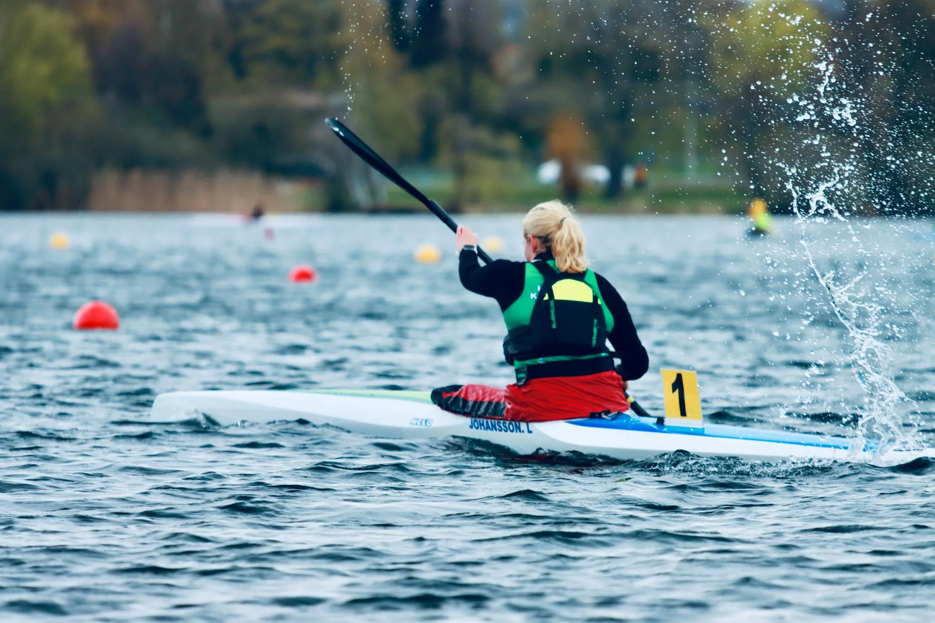 Kayaker mid-forward-stroke with paddle blade splashing water