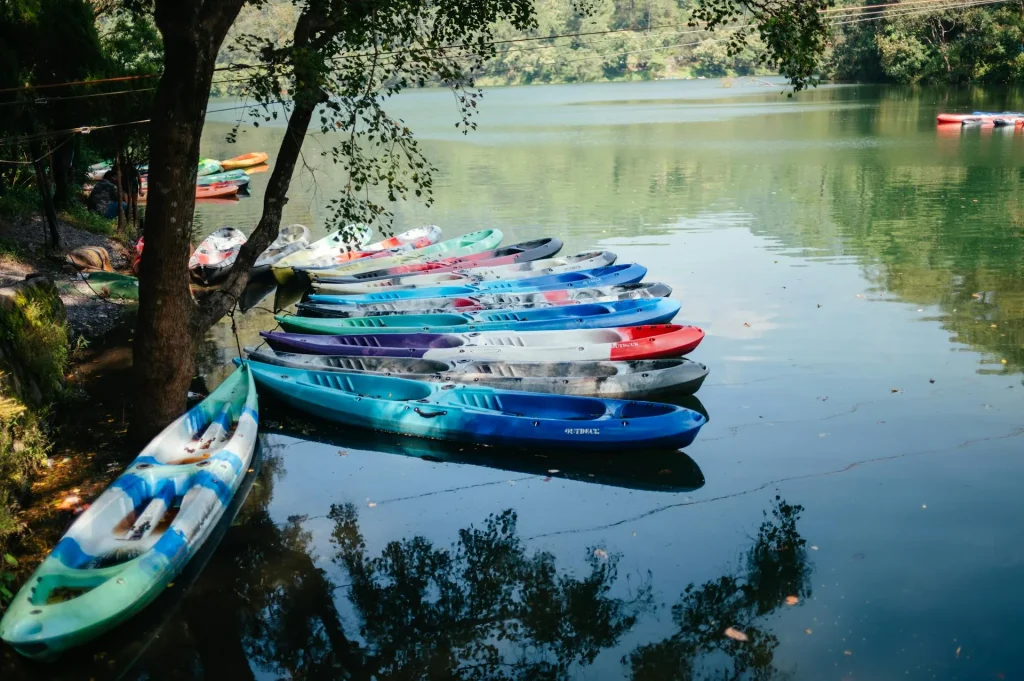 Colourful kayaks lined up on a tranquil lakeside showing different hull shapes