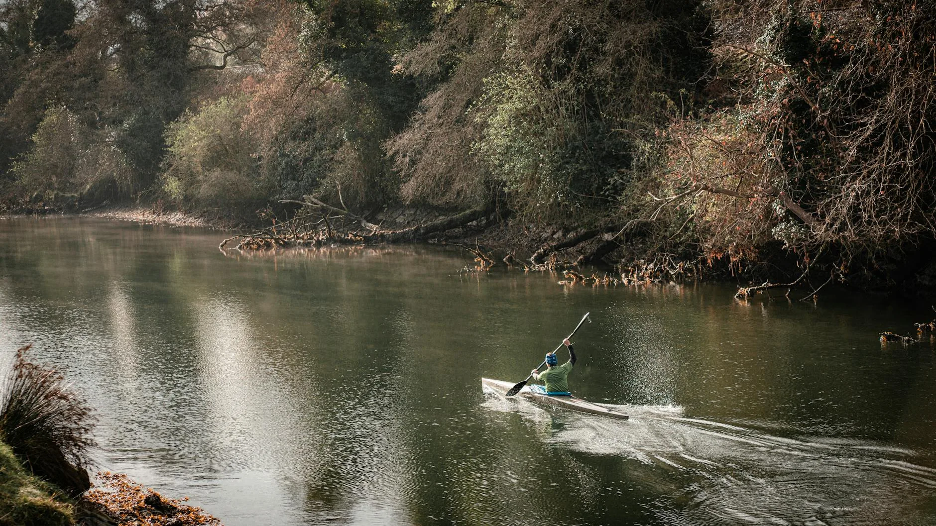 Kayaker paddling along a scenic river surrounded by greenery