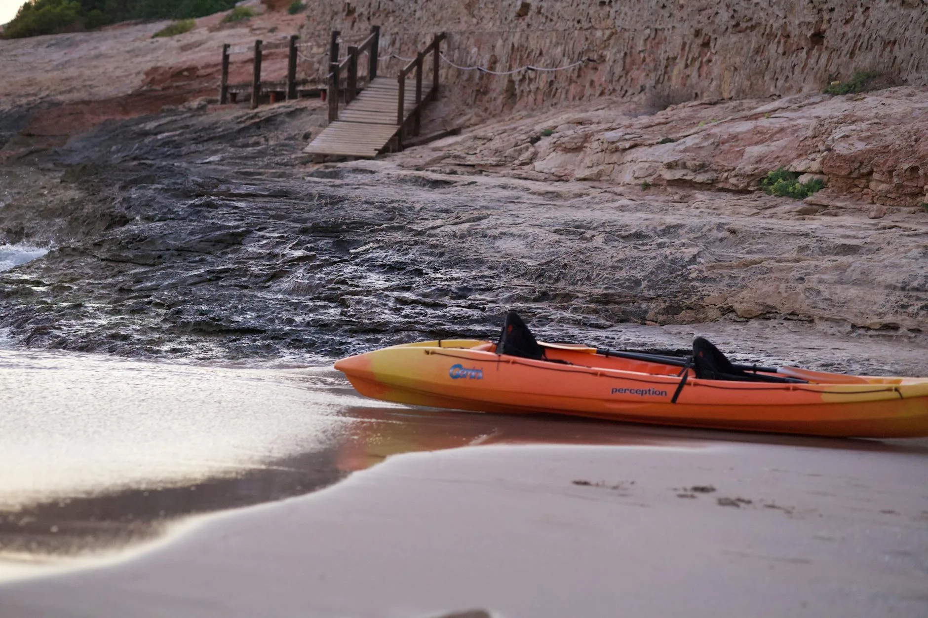 Fishing kayak on a sandy shore ready to launch into calm sea
