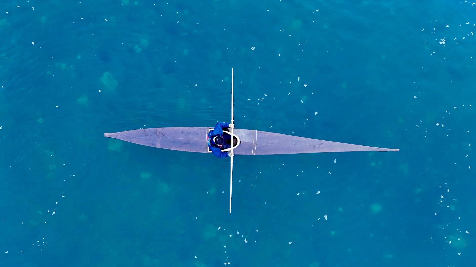 Solo kayaker paddling on calm water in a sit-in kayak