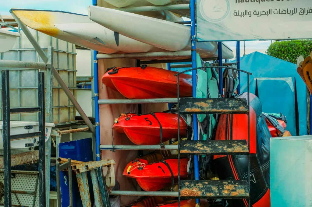 Colourful kayaks stacked on a rack outdoors at a rental shop
