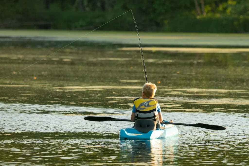 Child paddling a kayak on a calm lake with a correctly sized paddle