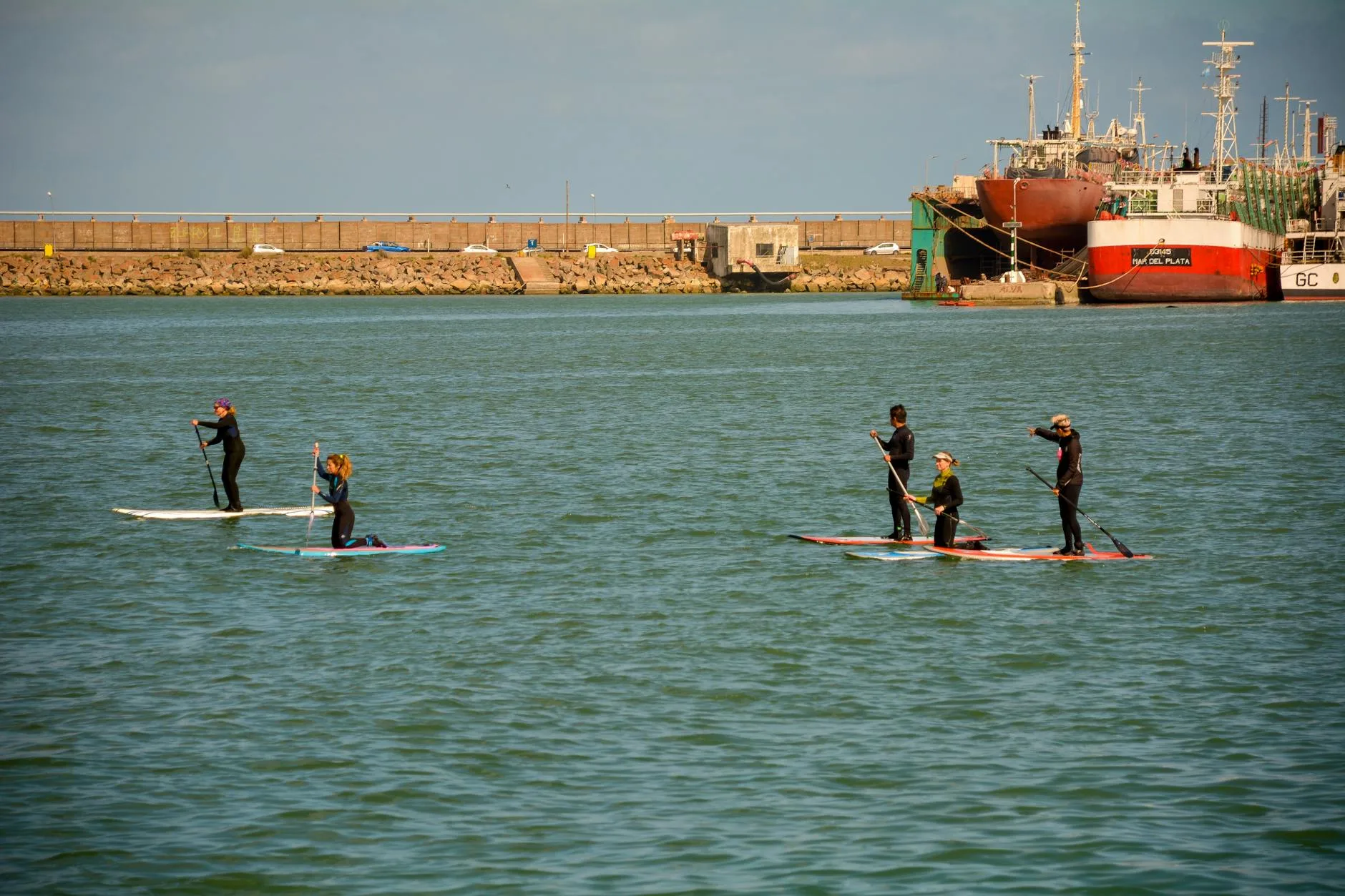 Paddleboarder on coastal waters wearing a wetsuit