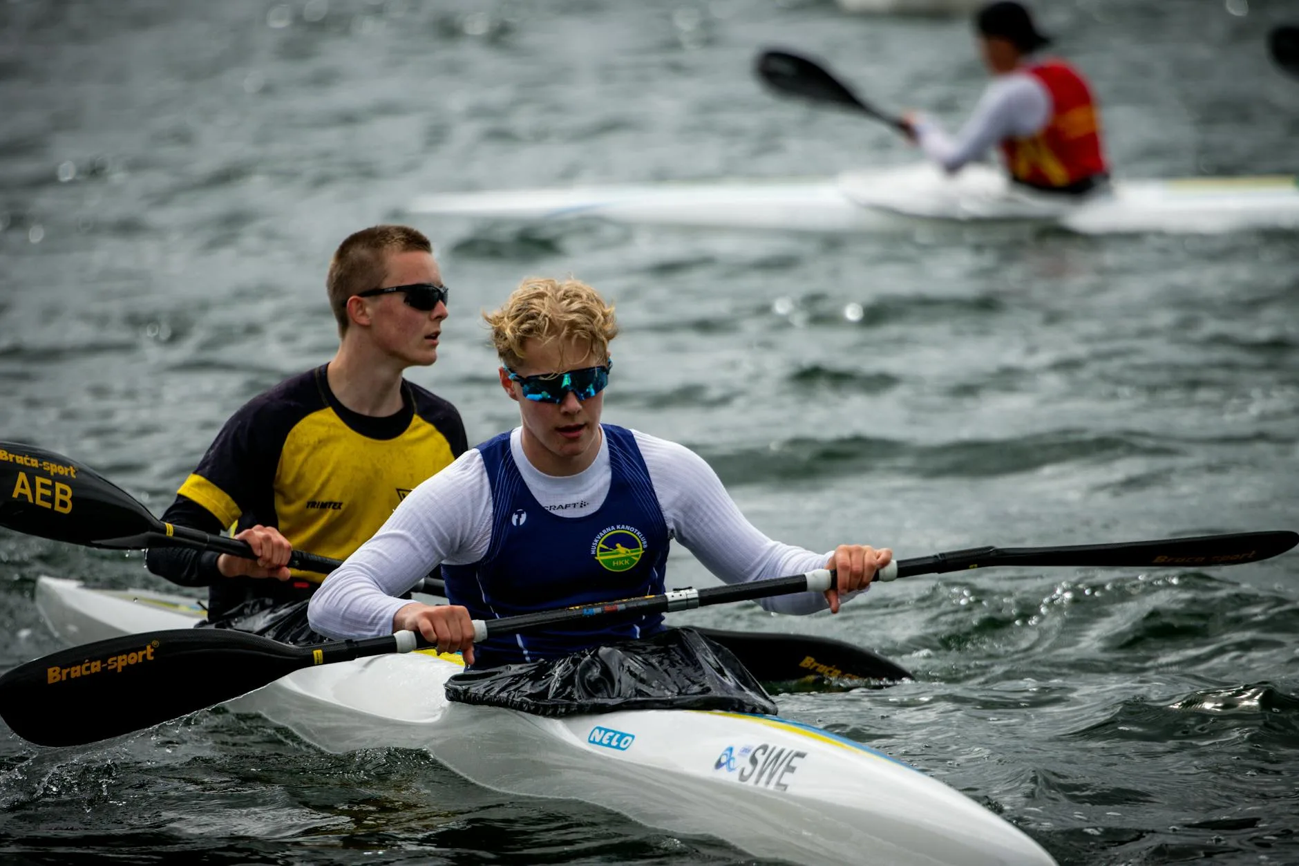 Sprint kayakers gripping paddles on open water
