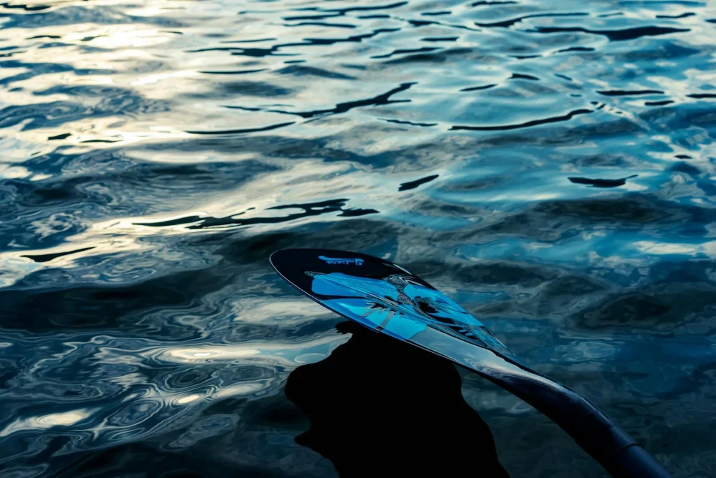 Kayak paddle resting on a dock beside calm water