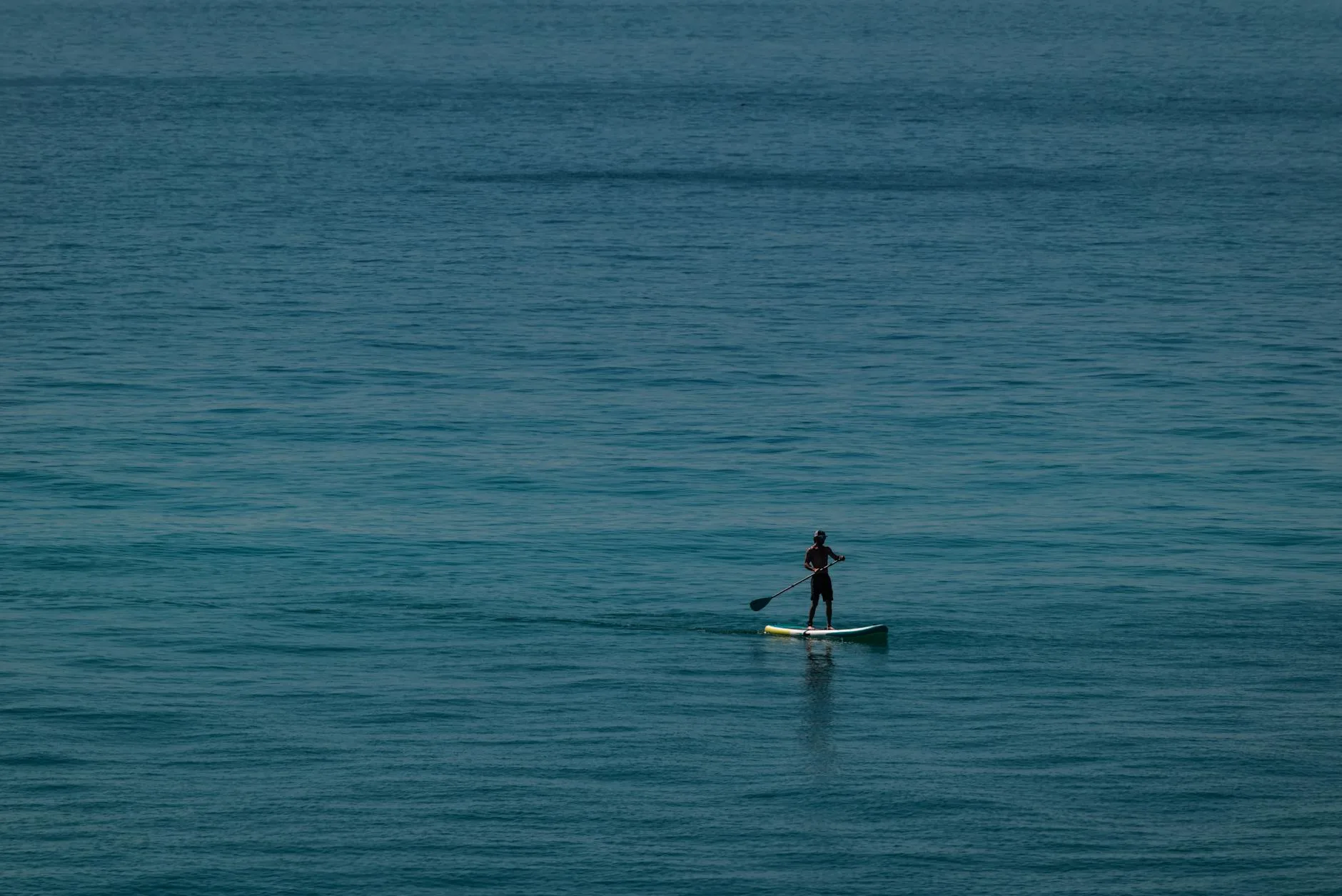 Stand up paddleboarder on open water with gear on deck