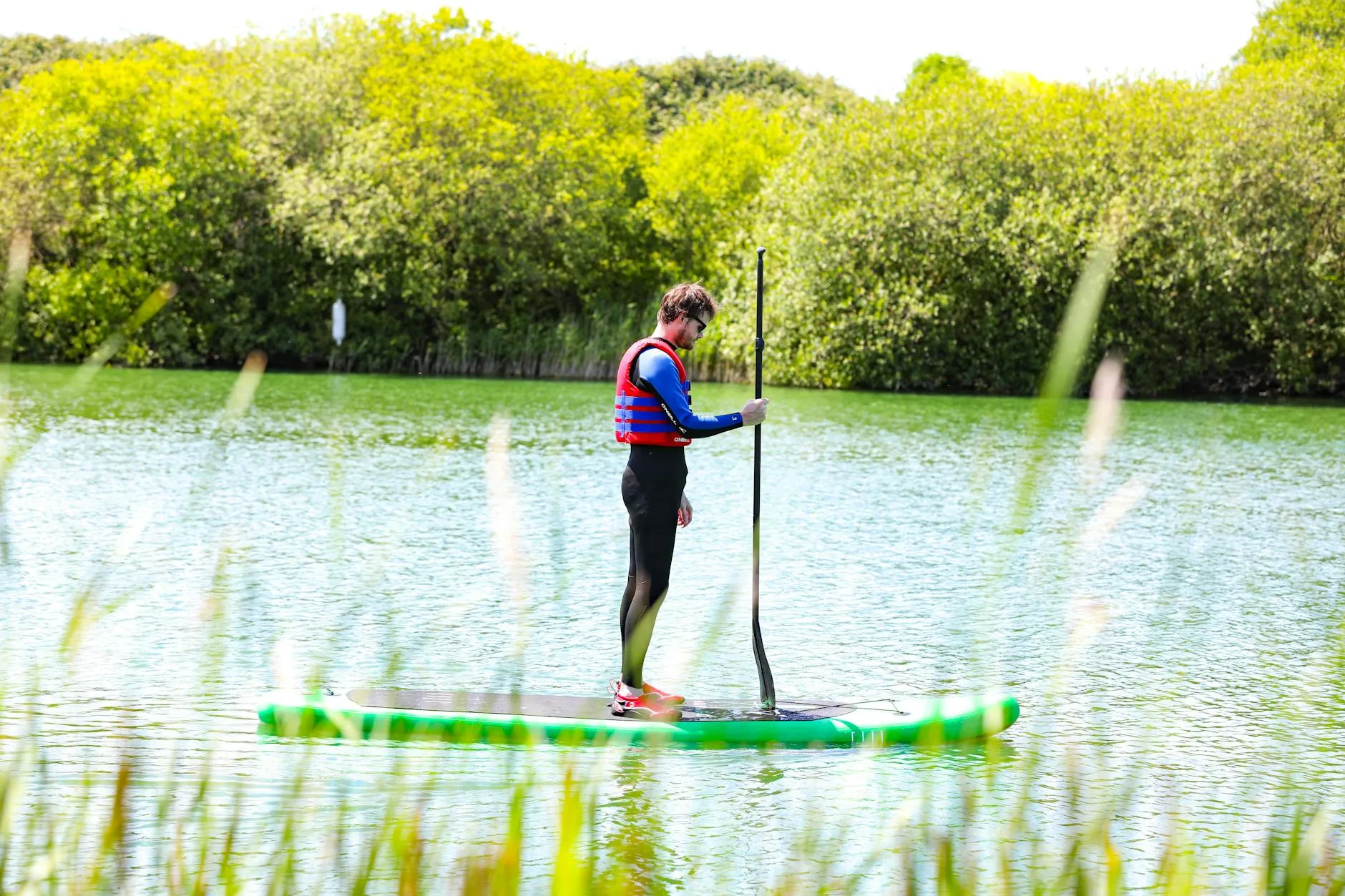 Stand up paddleboarder paddling on a calm river with correct paddle length