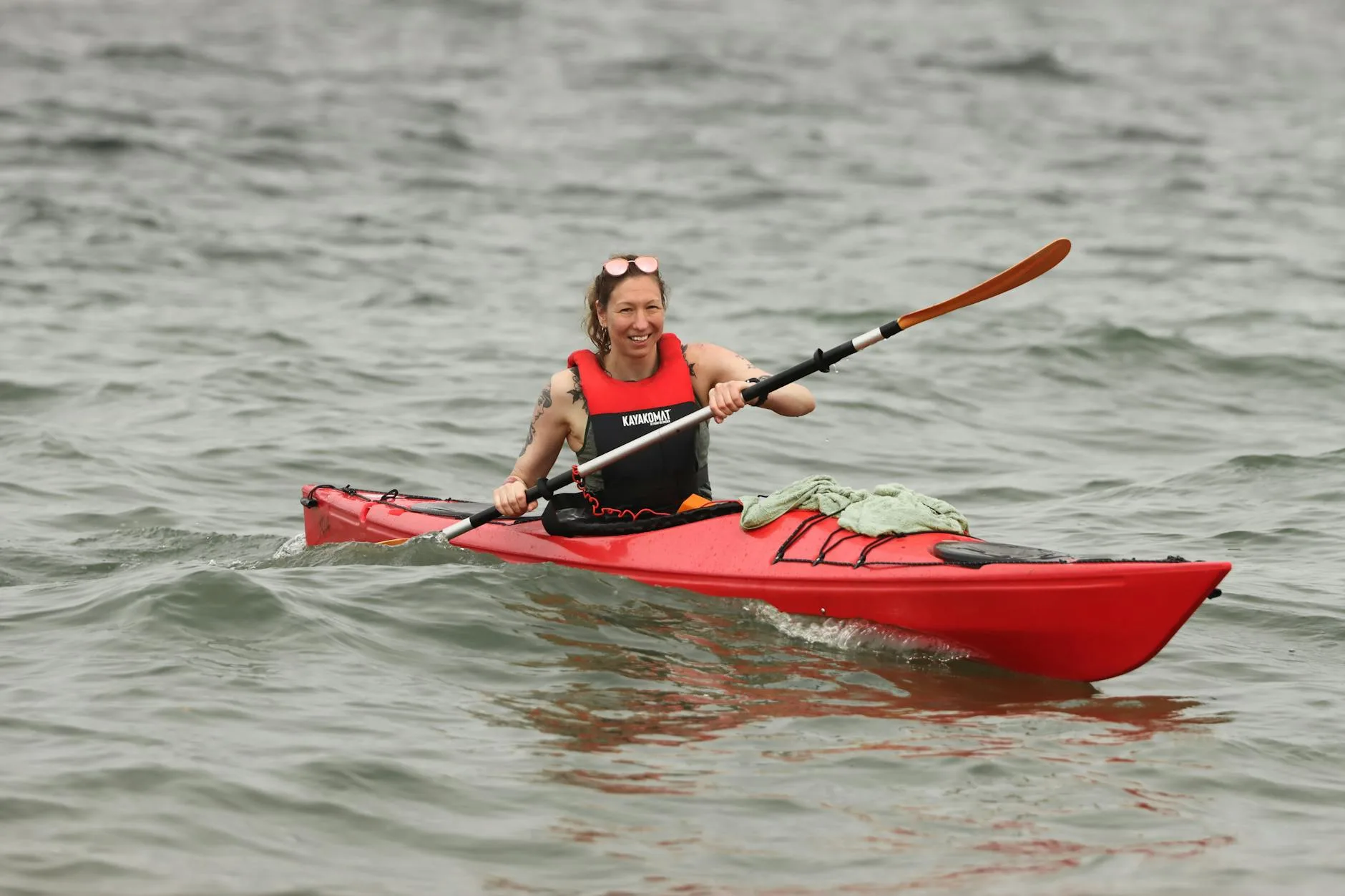 Kayaker in a red touring kayak wearing a buoyancy aid