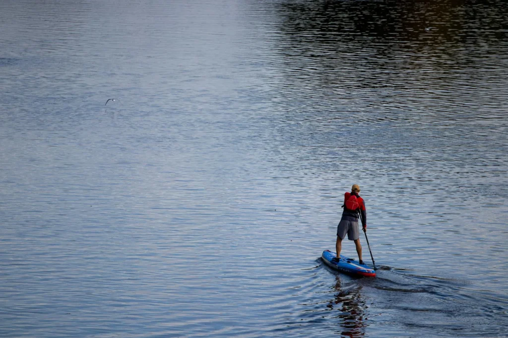 Person stand up paddleboarding on a calm lake