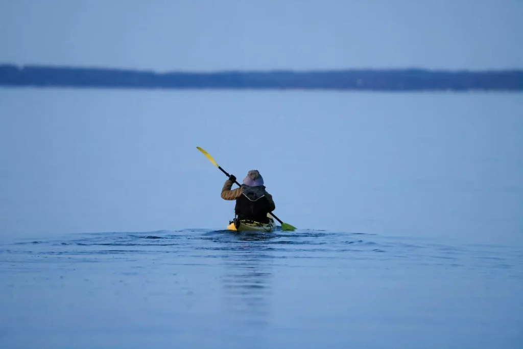 Person paddling a kayak on calm river water