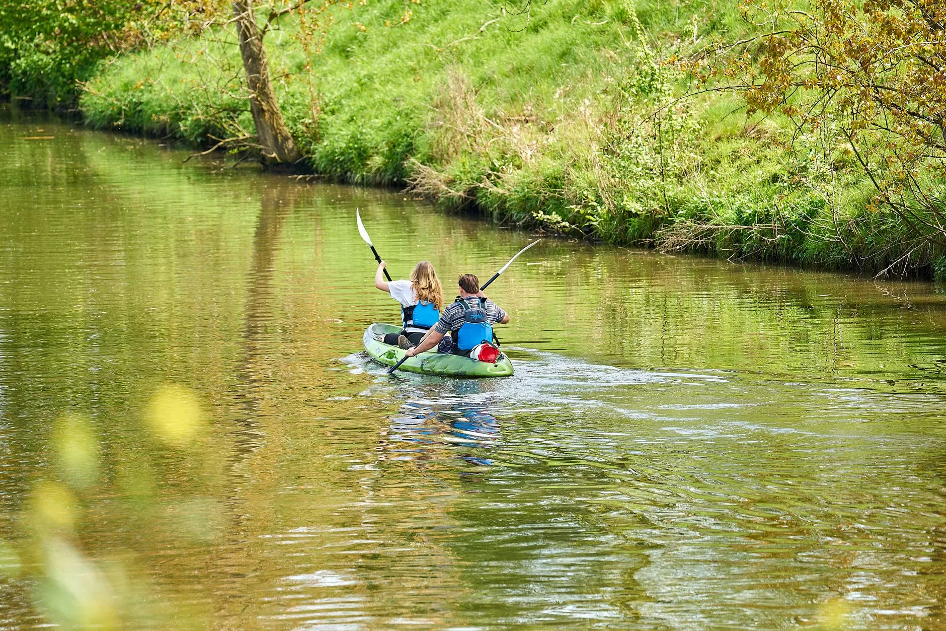 Kayaker holding a double bladed paddle with relaxed wrists on calm water