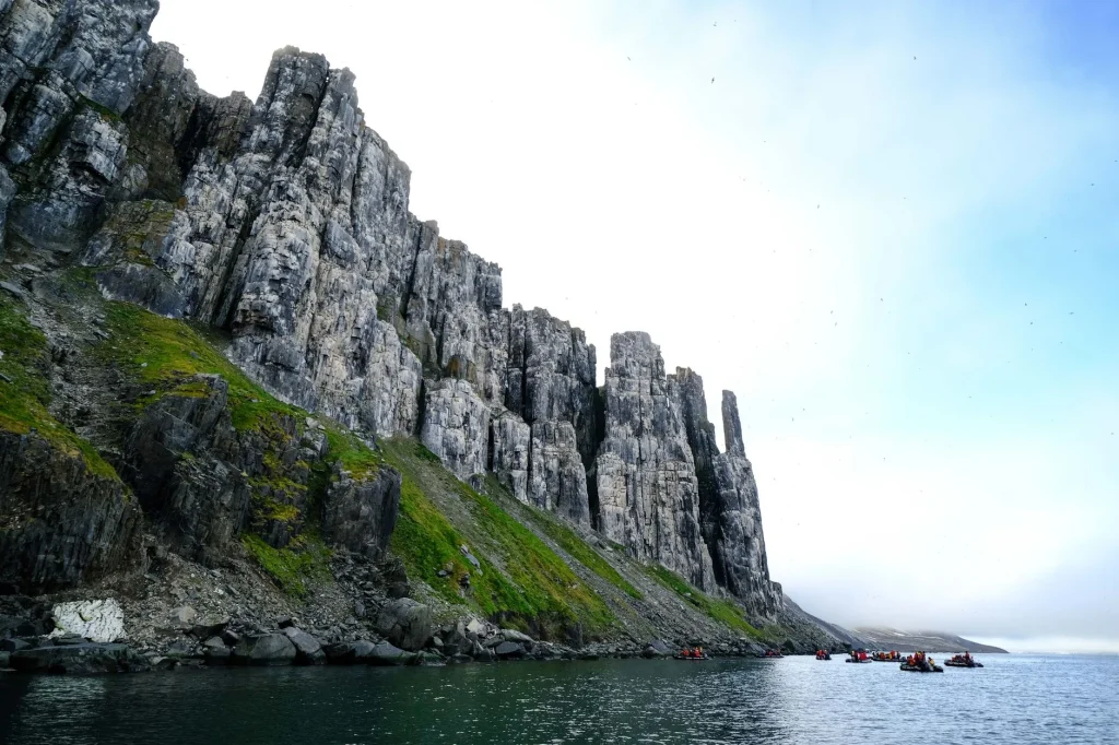 Sea kayak paddling on coastal water near cliffs