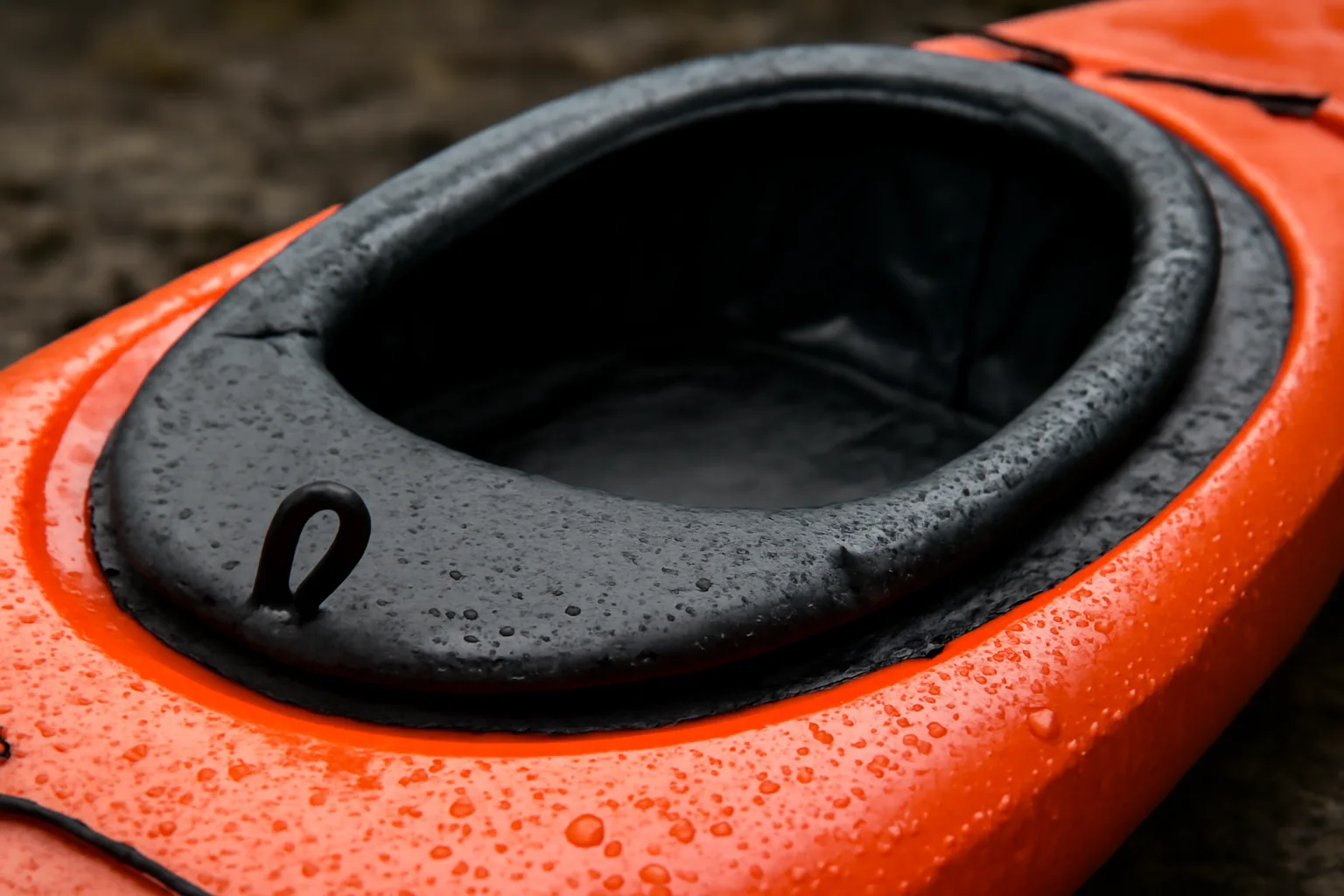 Black spray deck fitted around a kayak cockpit rim with grab loop visible