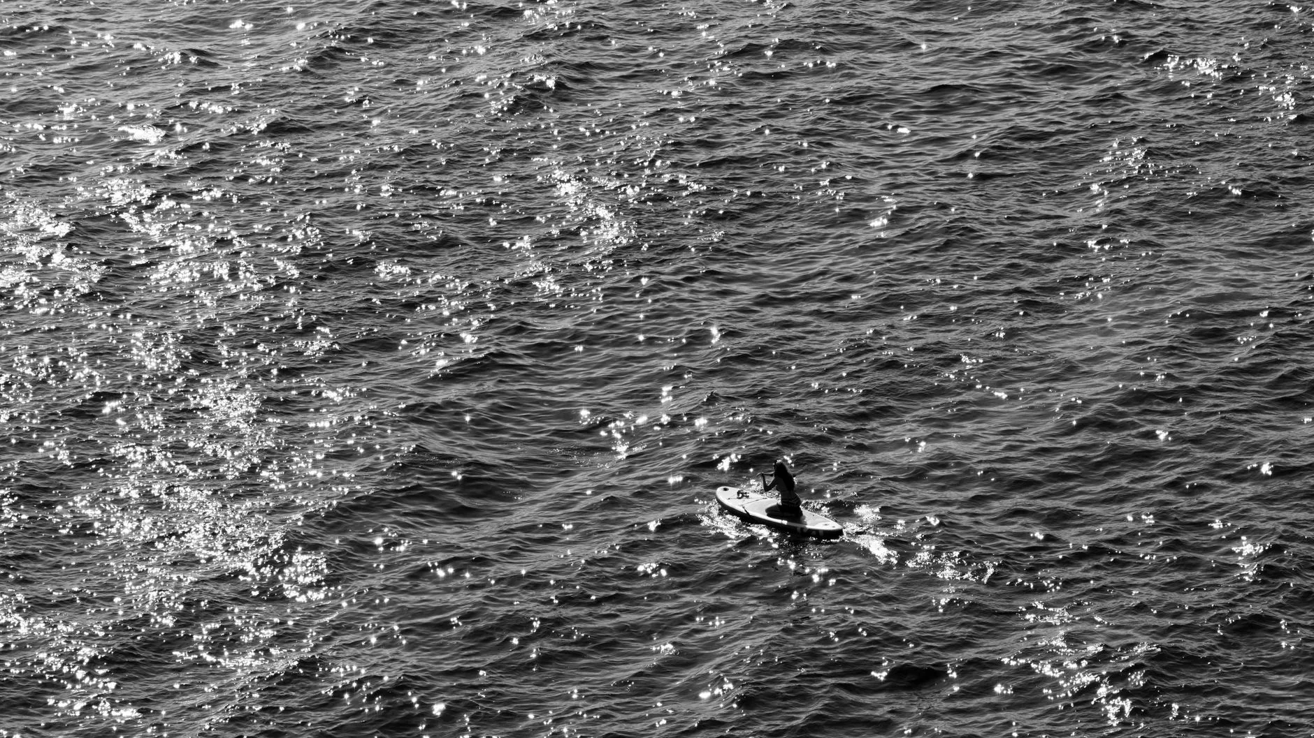 Stand up paddleboarder using efficient stroke technique on calm water