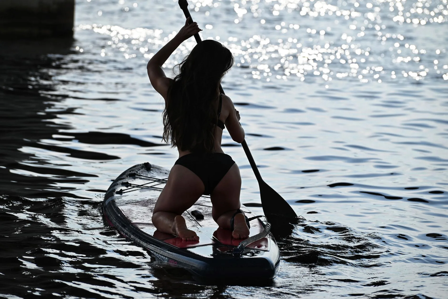 Paddleboarder using a sweeping paddle stroke to turn a SUP