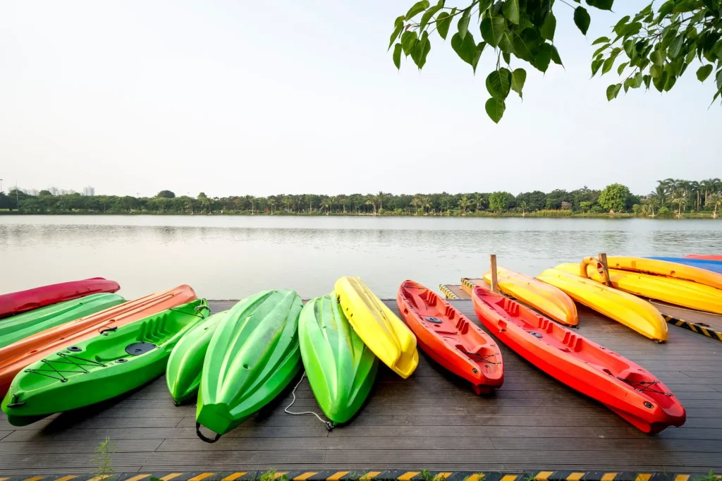 Inflatable and hard shell kayaks ready beside calm water