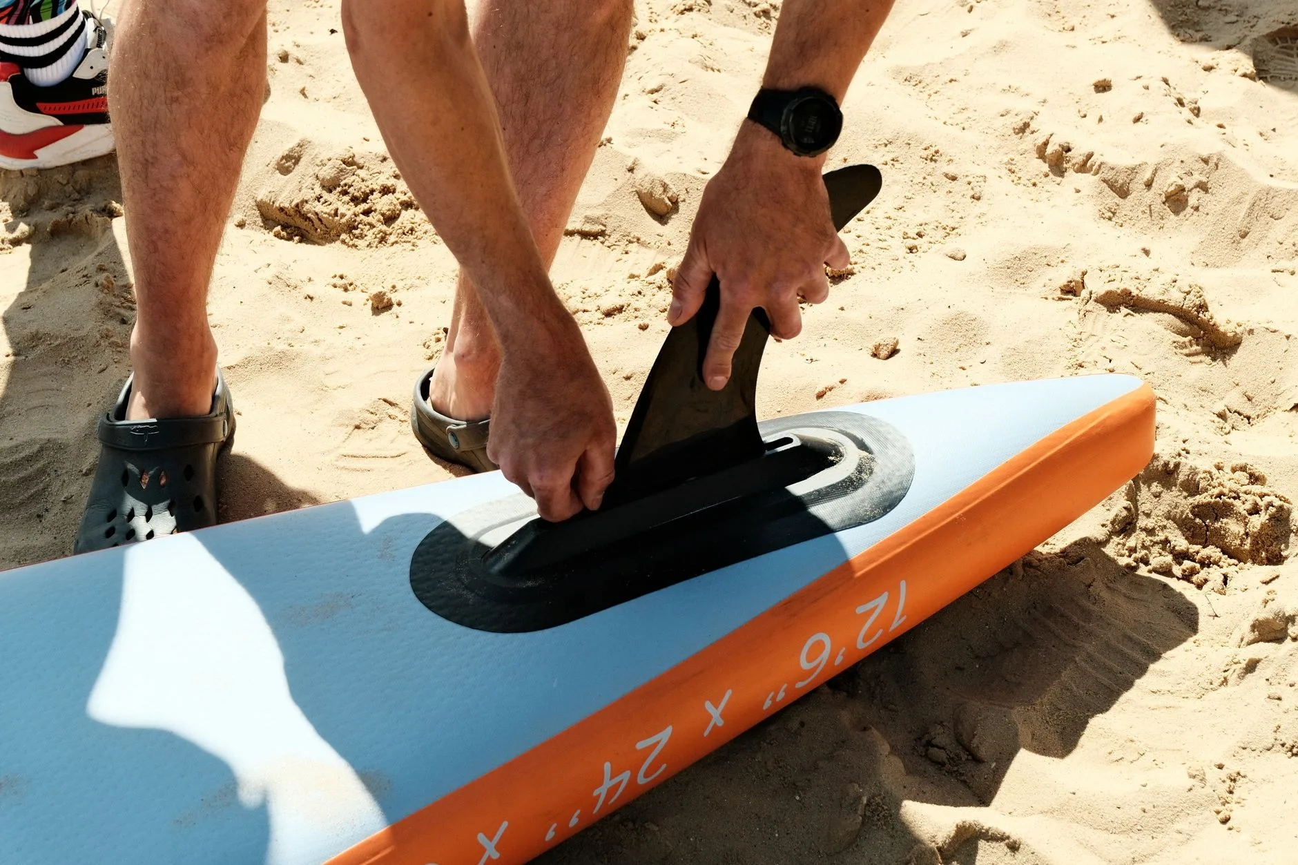 Paddleboard fin box and rail being checked during maintenance