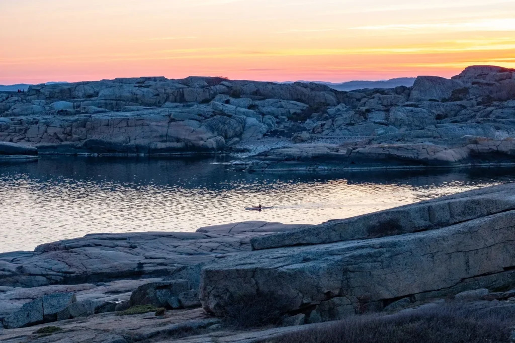Sea kayaker paddling near a rocky coastline on tidal water