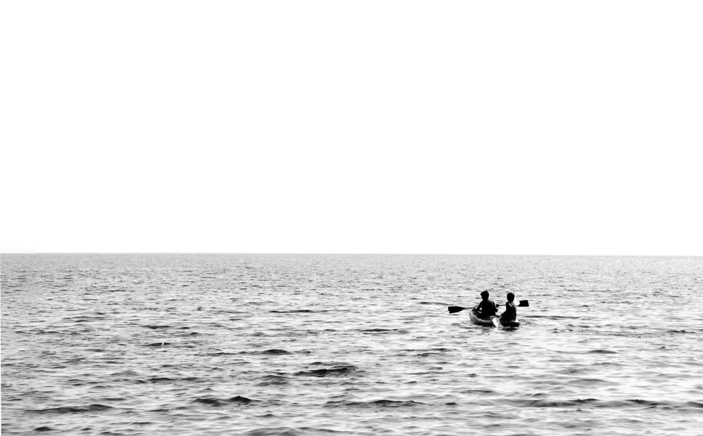 Two people paddling a tandem kayak on a calm lake