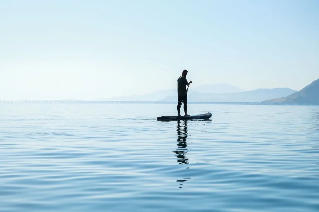 Paddleboarder wearing a wetsuit on calm UK water