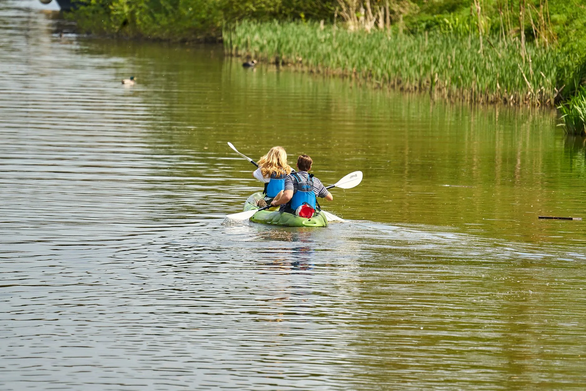 Couple paddling a double kayak together on sheltered water