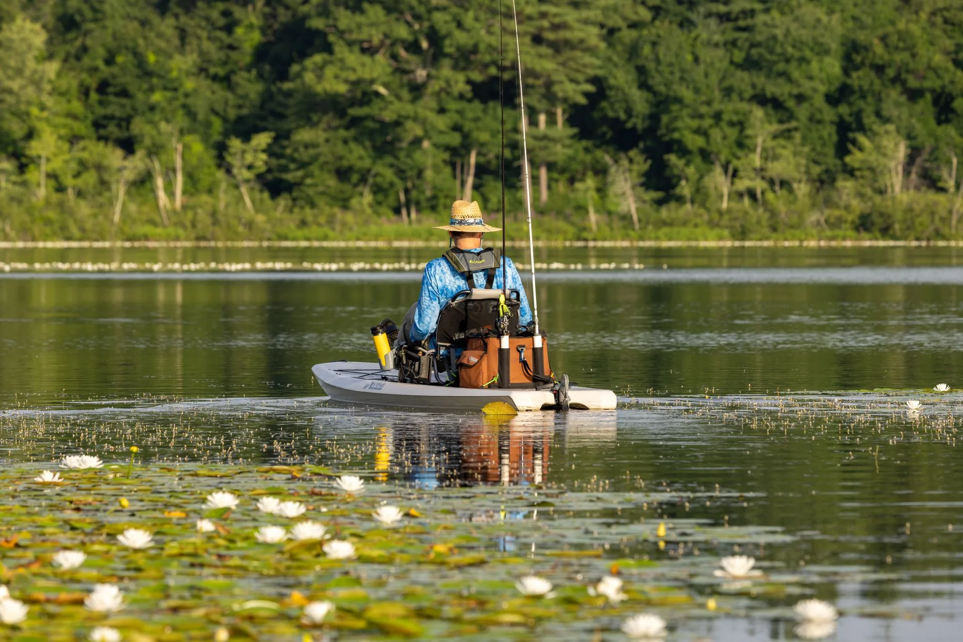 Adult angler using a fishing kayak with rods on calm water