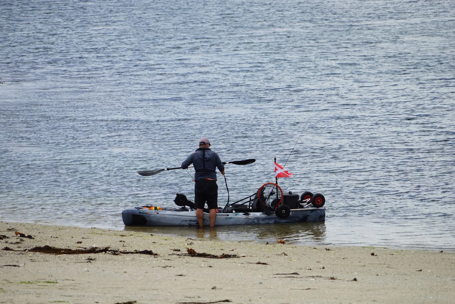 Adult angler launching a fishing kayak on open water