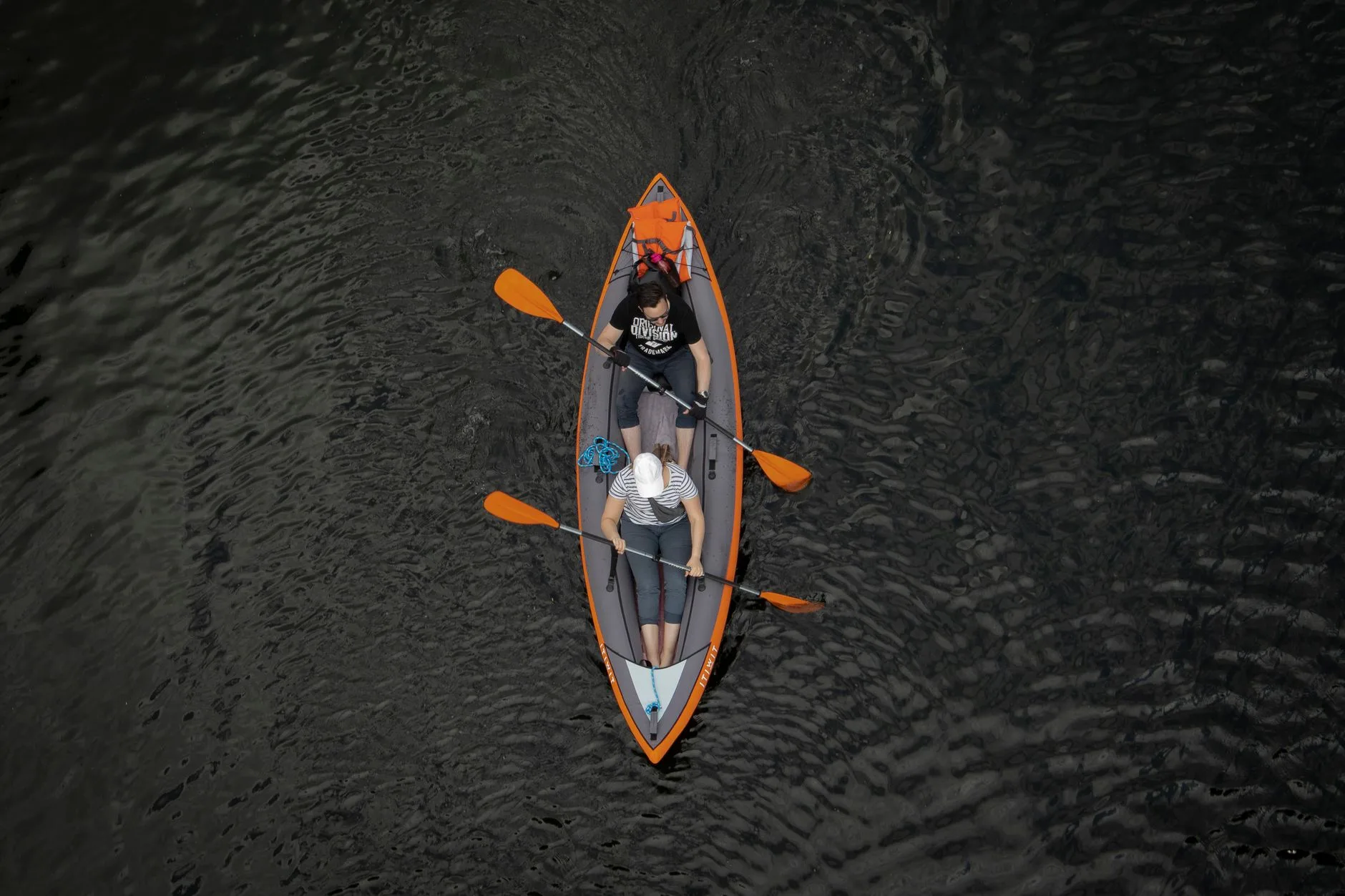 Two adults paddling a tandem kayak together on calm water